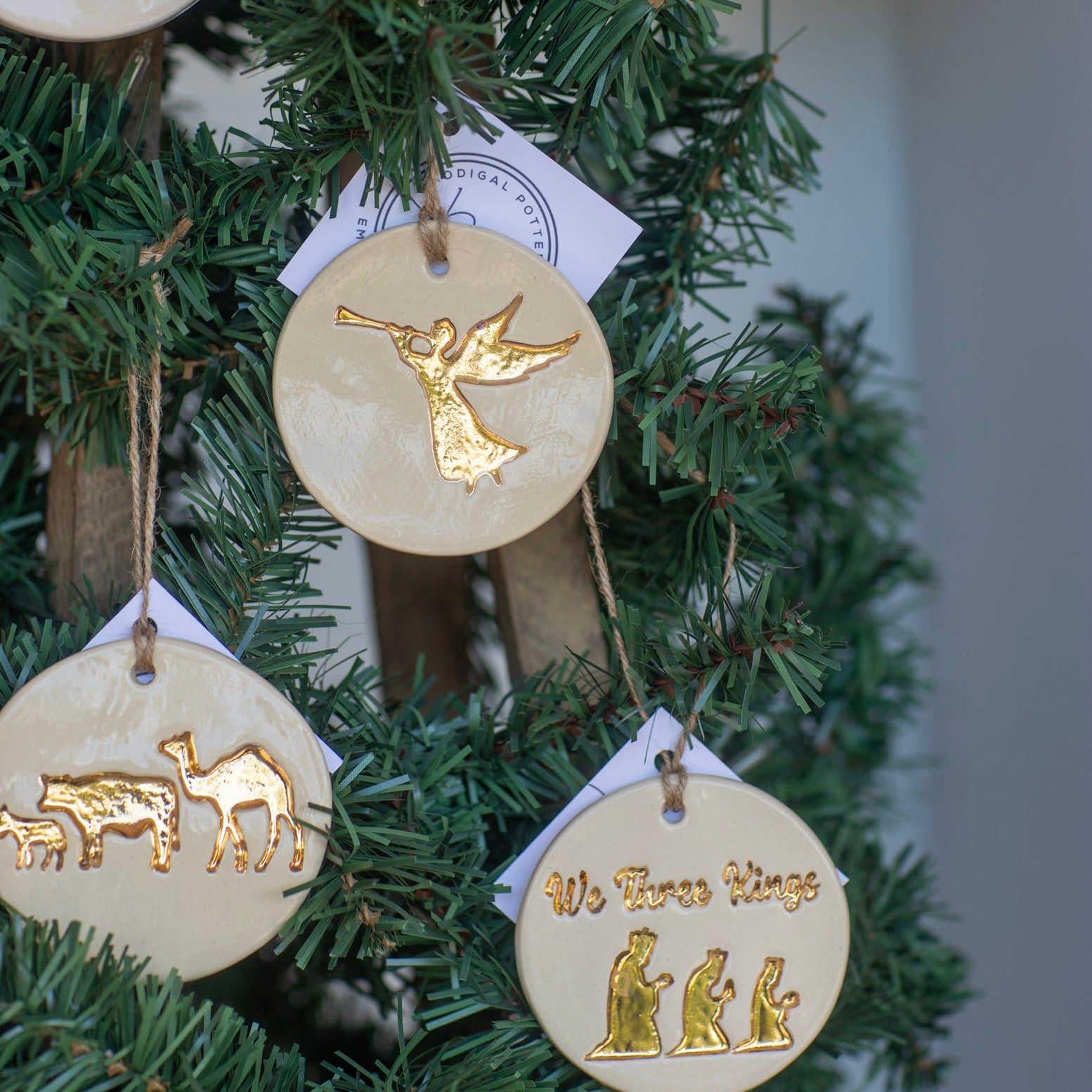 Decorative Christmas ornaments with gold angel, camel, and three wise men on a green wreath.