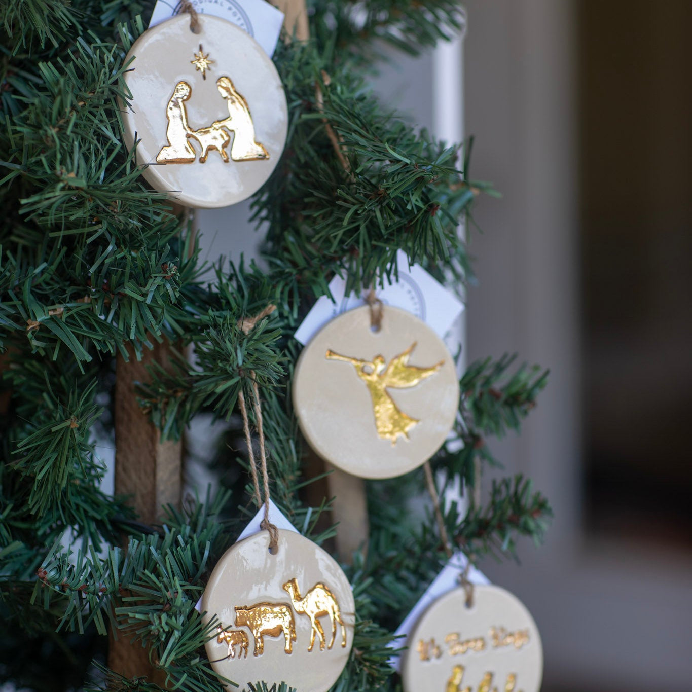 Decorative Christmas ornaments with gold figures on a green tree.