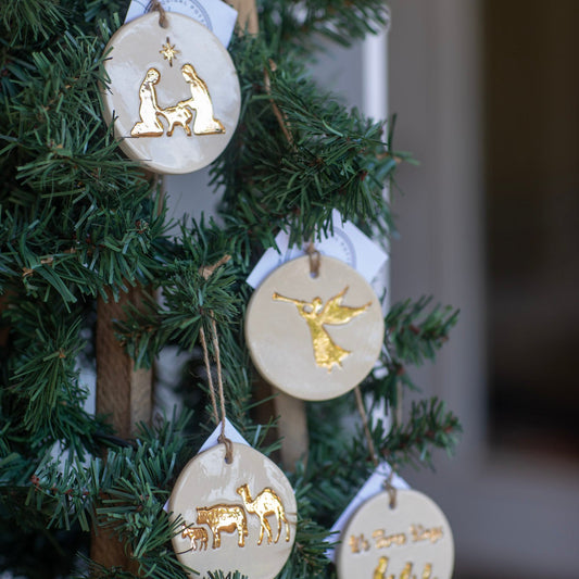Decorative Christmas ornaments with gold figures on a green tree.