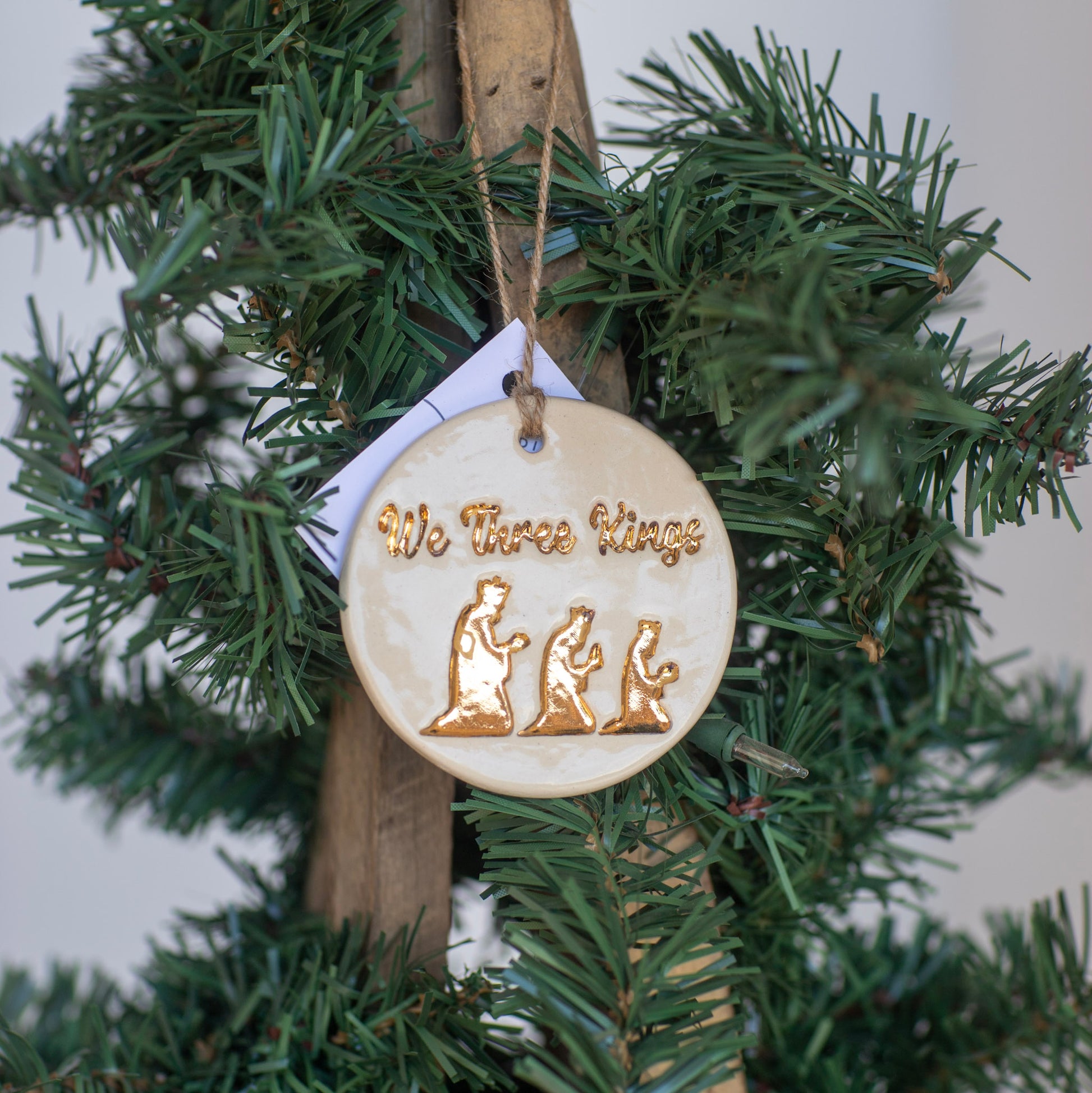 Decorative ornament with 'We Three Kings' text and figures on a Christmas tree.