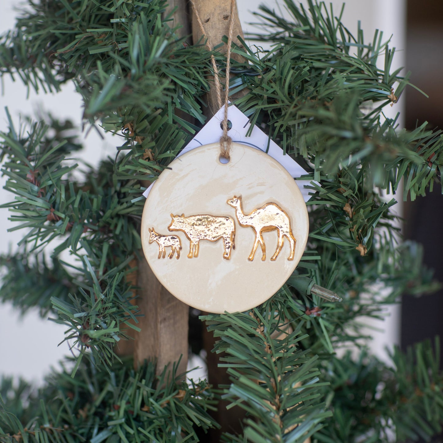 Decorative ornament with gold animal illustrations hanging on a Christmas tree.